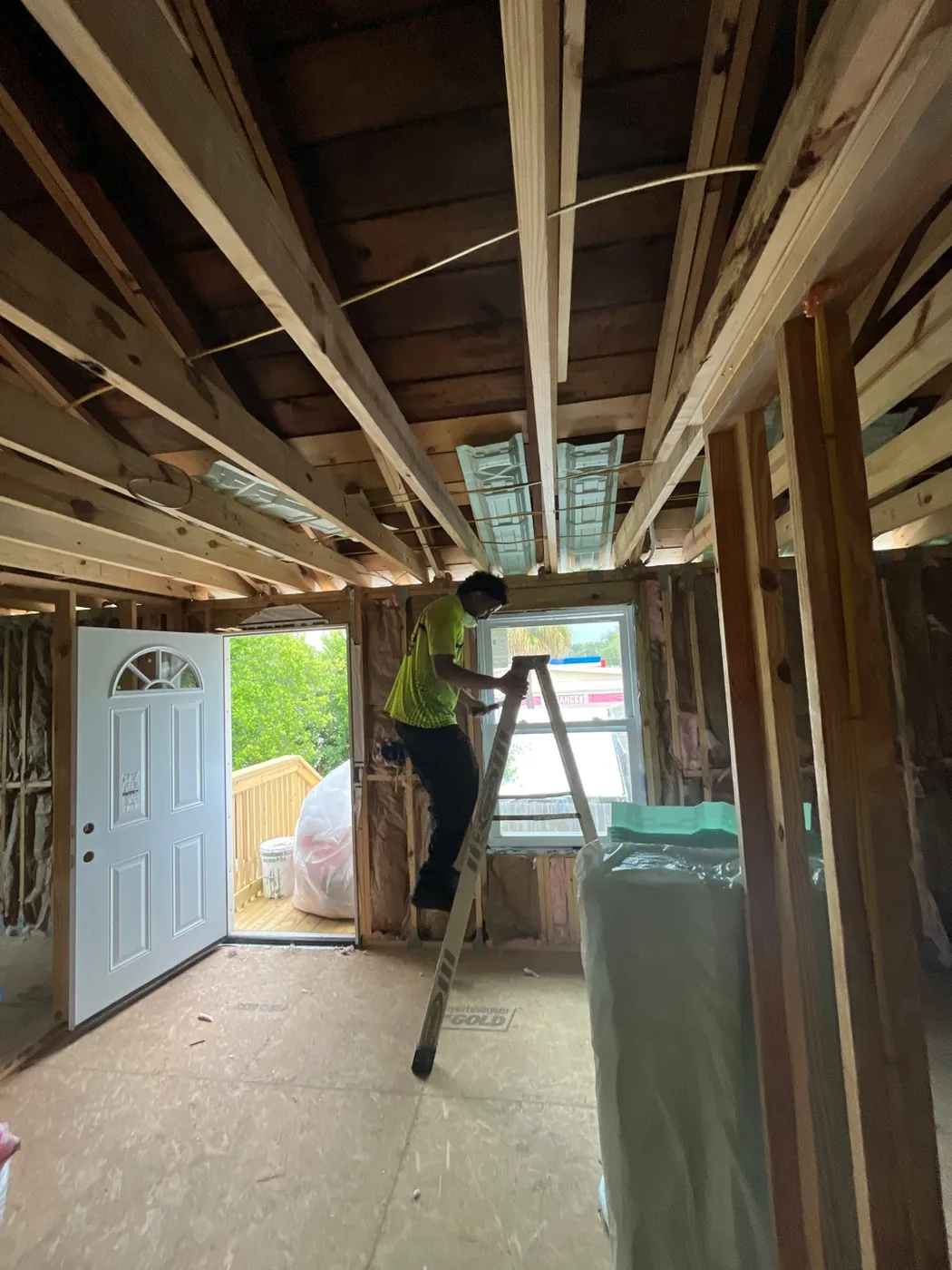 TLS installer fitting batt insulation at ceiling level during a whole-home insulation install in Tampa, FL 33609
